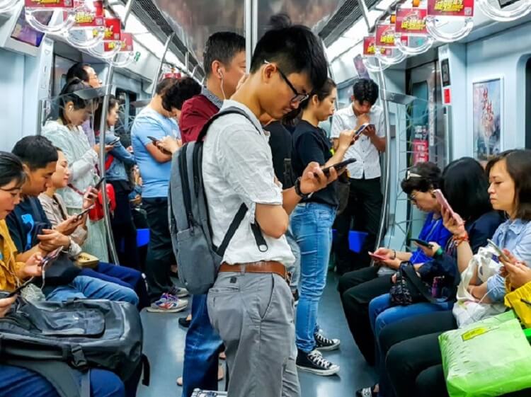 Chinese guy looking at phone on subway train