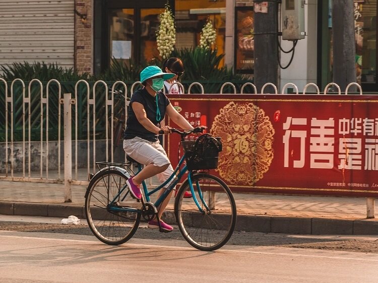 Woman wearing pollution mask while riding bicycle