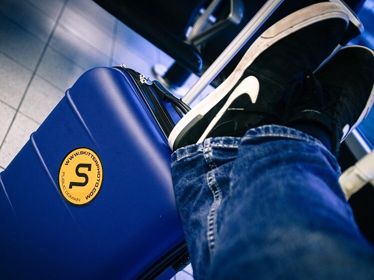 Person wearing jeans with feet on suitcase