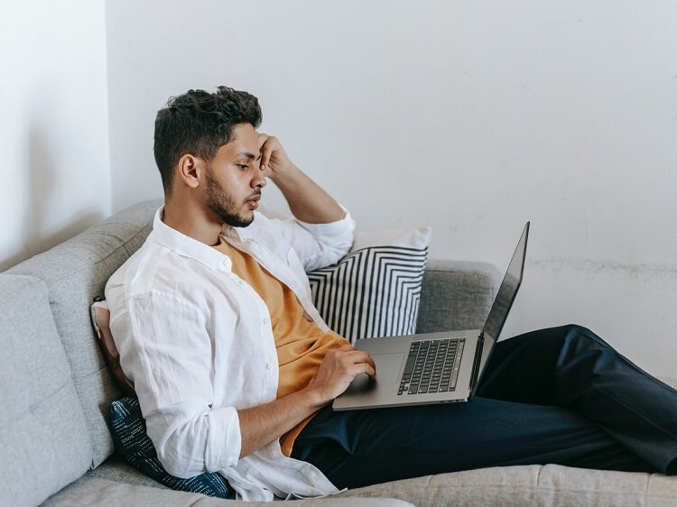 Man on couch looking for jobs online