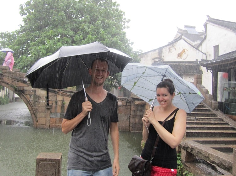 wet tourists standing under umbrellas in zhouzhuang water town