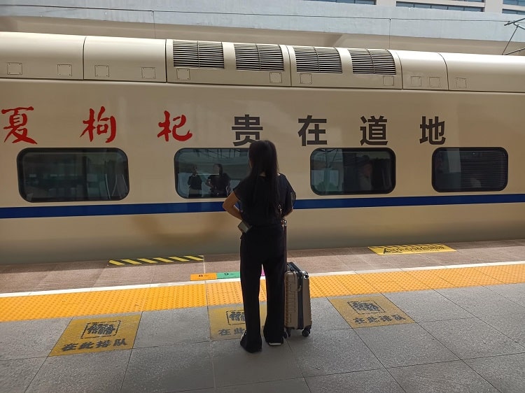 woman on platform while chinese bullet train is arriving
