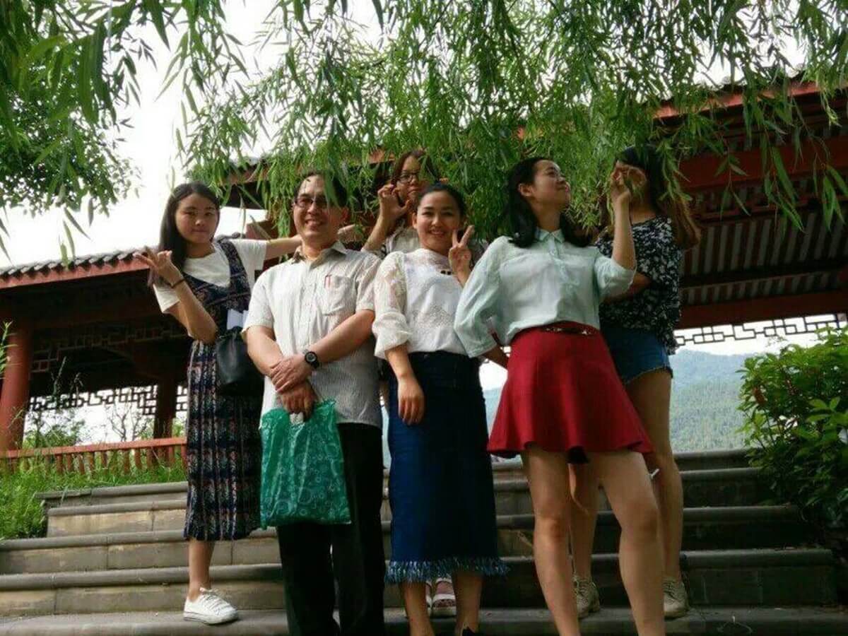 Chinese university students standing beneath tree with teacher