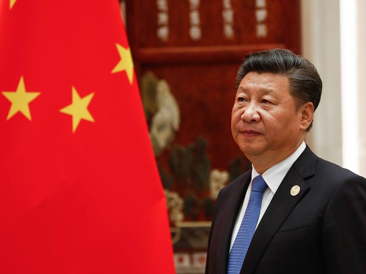 Xi Jinping standing next to Chinese flag